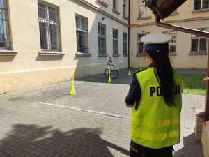 policjantka stoi tyłem w tle po torze rowerowym jedzie uczeń