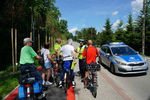 policjantka z grupą rowerzystów wręcza im odblaski