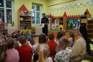 policjantka w czasie prelekcji stoi przodem do dzieci dzieci siedzą tyłem zdjęcie zrobione w sali