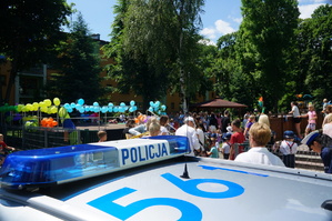 na pierwszym planie fragment radiowozu z napisem policja w tle piknik