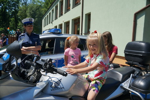 dziewczynka siedzi na motocyklu policyjnym obok stoi policjantka