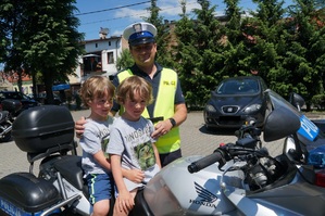 dwóch chłopaków siedzi na motocyklu obok stoi policjant