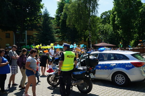 policjant radiowóz i motocykl obok uczestnicy festynu
