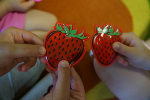 dłonie dziecięce które trzymają odblask w kształcie truskawki