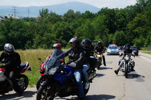 motocykliści jadący po drodze za nimi widoczny radiowóz