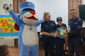 obok siebie stoją sznupek policjanci i krzysiu z prezentem