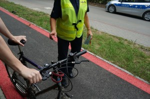 fragment rowerzysty i policjantki w tle radiowóz