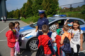 obok radiowozu stoi policjantka i dzieci