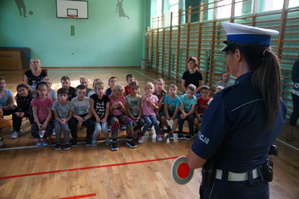 policjantka stoi tyłem przed nią przodem siedzą dzieci w ławkach