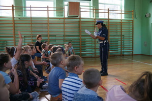 policjantka w czasie prelekcji w ławkach siedzą uczniowie i zgłaszają się