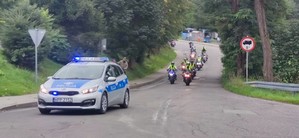 na pierwszym planie radiowóz w tle jadący po drodze motocykliści