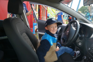 chłopczyk siedzi w radiowozie ma założoną policyjną czapkę