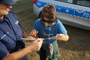 chłopczyk w założonych narkogooglach próbuje przeczytać książkę obok stoi policjantka