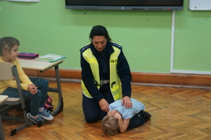 policjantka wspólnie z uczniem pokazuje jaką przyjąć postawę w przypadku kontaktu z niebezpiecznym zwierzeciem