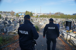 policjanci tyłem idą przez cmentarz