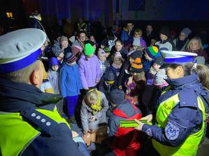 na zdjęciu obok siebie policjantka i policjant w tle stoją uczestnicy akcji na ziemi leży fantom