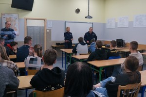 policjantka oraz policjant w czasie prelekcji, uczniowie siedzą tyłem w ławkach, zdjęcie kolorowe zrobione w sali lekcyjnej