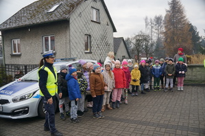zdjęcie kolorowe zrobione na zewnątrz obok radiowozu stoi policjantka i dzieci