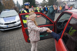 na zdjęciu widać dziecko która wręcza kierowcy cytrynkę w tle widać policjantkę i inne dzieci