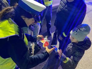 na zdjęciu policjantka daje odblask dziecku