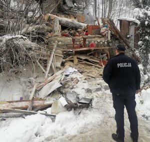 kolorowe zdjęcie policjant stoi tyłem w tle zburzony budynek