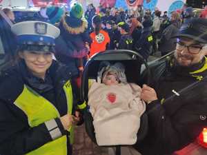 na zdjęciu policjantka obok mężczyzna z dzieckiem w wózku w tle mieszkańcy i organizatorzy akcji