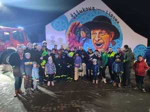 zdjęcie grupowe stoją organizatorzy akcji wóz strażacki i mieszkańcy w tle mural z napisem śliwkowa gmina lipowa