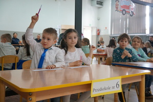 przedszkolaki siedzą przy stoliku zgłaszają się do odpowiedzi