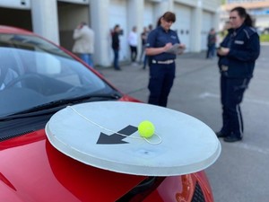 na pierwszym planie fragment samochodu z tzw. talerzem stewarda w tle dwie policjantki
