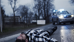 osoba leżąca na przejściu dla pieszych w tle radiowóz