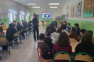 zdjęcie kolorowe zrobione w sali uczniowie siedzą w ławkach policjantka prowadzi prelekcje