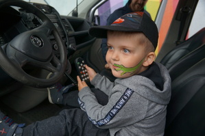 zdjęcie kolorowe dziecka siedzącego za kierownicą radiowozu