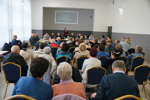 zdjęcie kolorowe zrobione w sali tyłem siedzą uczestnicy debaty komendnat komisariatu wita przybyłych gości