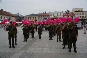 uczniowie stoją w kształcie wstążki z różowymi balonikami