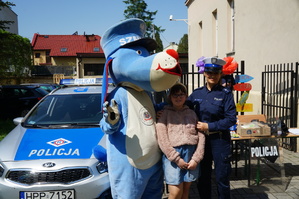 radiowóz, sznupek  policjantka i dziewczynka stoją koło siebie