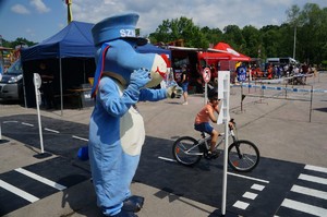 chłopczyk jedzie na rowerze po miasteczku ruchu drogowego obok niego stoi sznupek