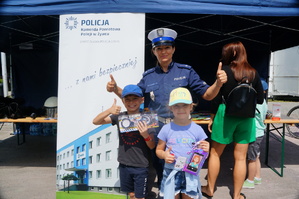 policjantka stoi przy stoisku z dziećmi które wygrały nagrody