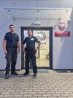 policjanci stoją obok siebie na tle budynku komisariatu