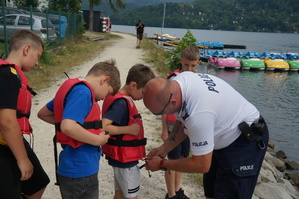 policjant poprawia dzieciom kamizelki ratunkowe