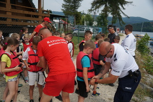 policjanci i ratownik wopru poprawia dzieciom kamizelki ratunkowe