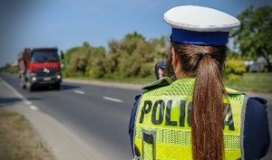 policjantka stoi tyłem dokonuje pomiaru prędkości w tle samochód