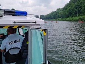 zdjęcie kolorowe policjanci siedzą w łódce w tle jezioro