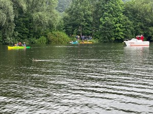 łódka woprowska i kajakarze pływający po jeziorze oraz stojący na brzegu