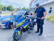 policjant stoi przy motorze na którym siedzi dziecko