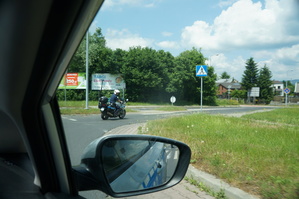 zdjęcie z wnętrza radiowozu widać z przodu jadącego na motocyklu policjanta