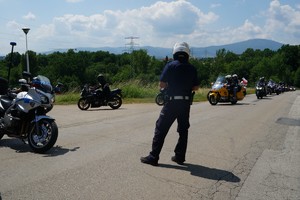 na drodze stoi policjant obok motor po drodze jadą motocykliści