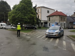 na zdjęciu policjant kierujący ruchem obok radiowóz