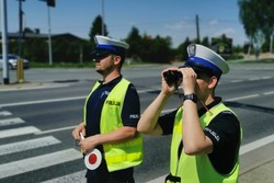 policjanci w czasie służby jeden patrzy przez lornetkę