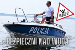 policjant stoi na motorówce obok napis bezpiecznie nad wodą