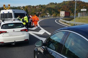 zaparkowany samochód oraz radiowozy na drodze obok policjanci